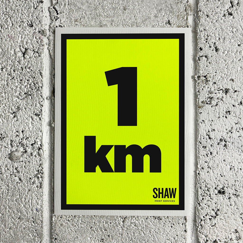 A 1KM distance marker sign on a yellow background with black text.