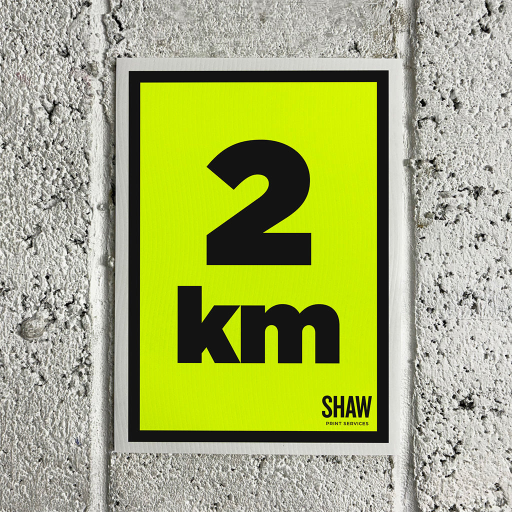 A 2KM distance marker sign on a yellow background with black text.