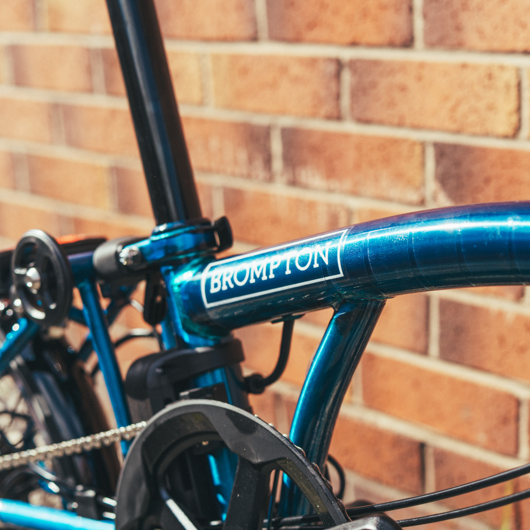 Blue Brompton bicycle against a brick wall
