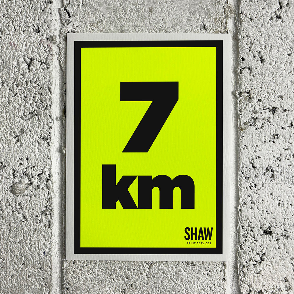 A 7KM distance marker sign on a yellow background with black text.