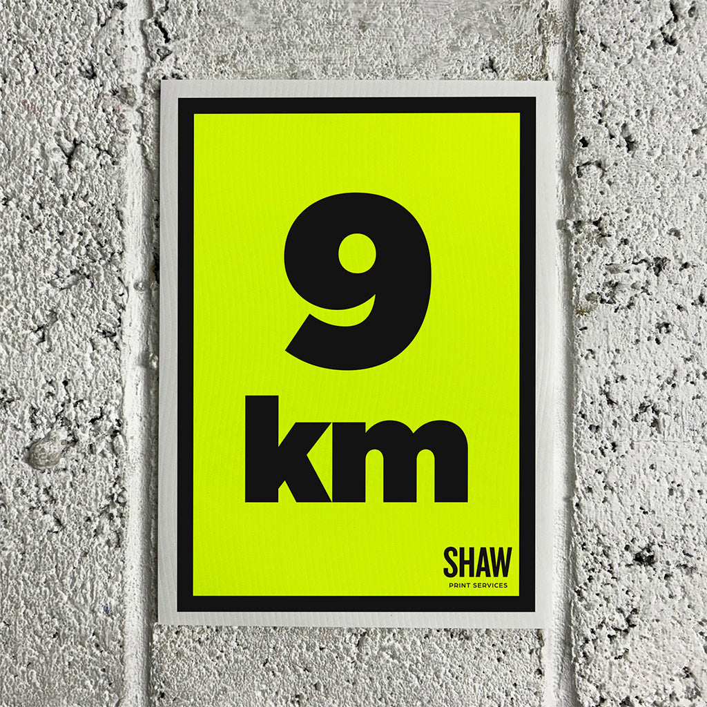 A 9KM distance marker sign on a yellow background with black text.