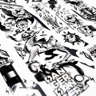 Collection of black and white designs featuring dragons, dice, and other symbols.