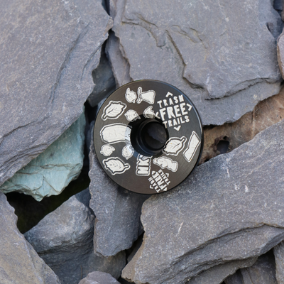 Trash Free Trails Black Stem Cap on grey stones.