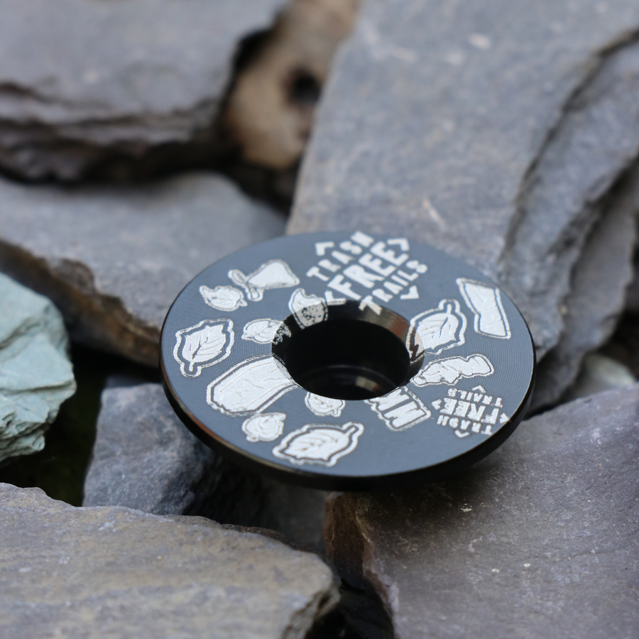 Trash Free Trails Black Stem Cap on grey stones.