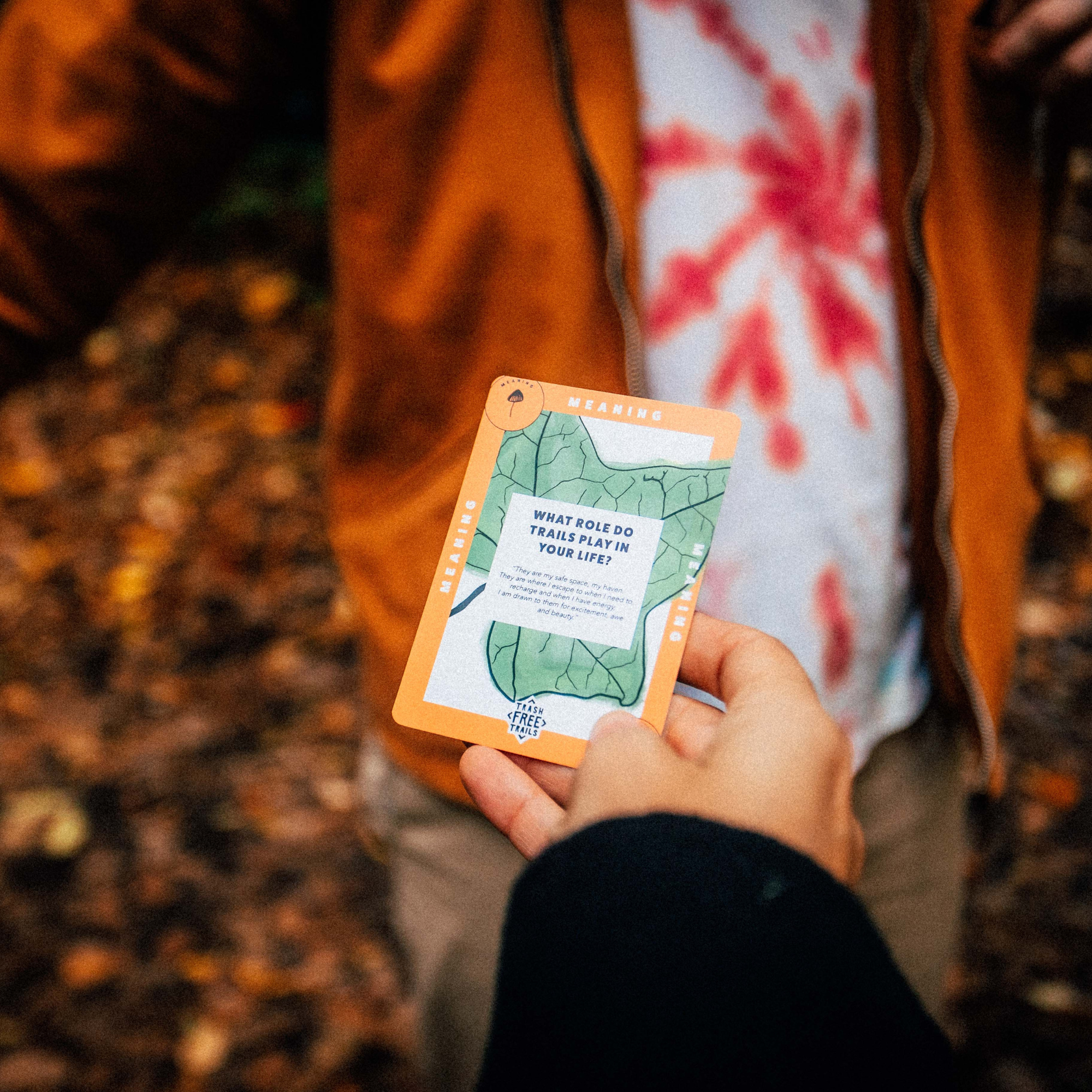 Person holding a nature-themed card in a forest setting