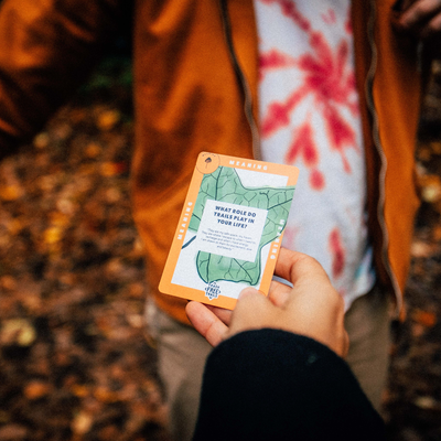 Person holding a nature-themed card in a forest setting