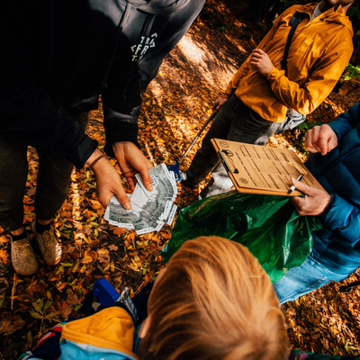 People gathered around a map on the ground with autumn leaves
