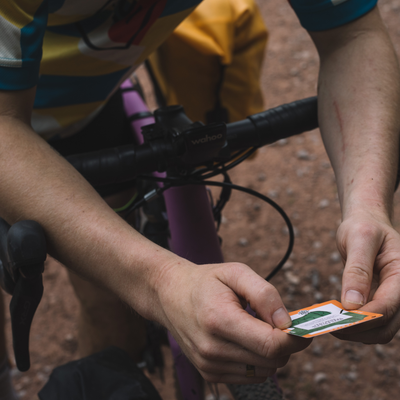 Person holding a small card with a green logo on a bike handlebar